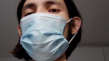 Yüzünün alt kısmını kaplayan cerrahi maske takan bir adam. Tıbbi ve sağlık sigortası konsepti. O ciddi bir ifadeyle doğrudan kameraya bakarak konuşur. Adam hayır diyerek başını sallıyor.