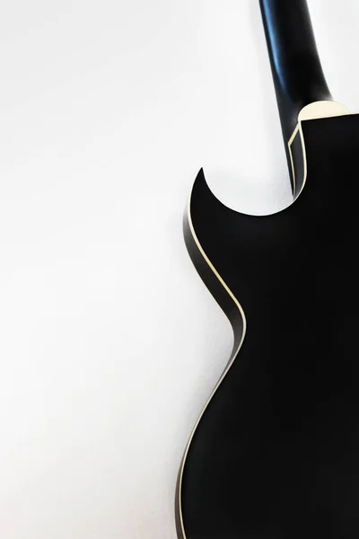 ブラックのエレキロックギターの滑らかな形状のシルエットと鋭いホーンテノンホワイトの壁の背景 中空鋼弦ジャズロックトップギター — ストック写真