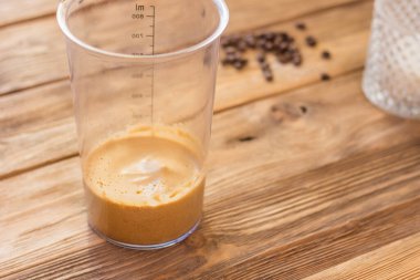 Dalgalı kahve, krem şantili kahve, latte köpüğü. İçki tarifi. Mutfak çırpıcı ile köpük çırpma işlemi. Mutfak masasında şeker kavanozu ve kahve ile ölçü kupası.