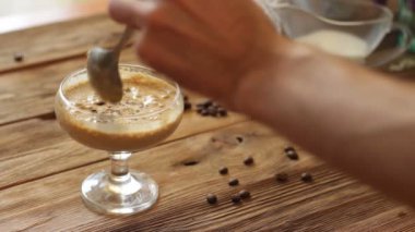 Dalgalı kahve, krem şantili kahve, latte köpüğü. İçmek yemek tarifi. Şeker kavanozu, kahve ve çiçeklerle hayat dolu. Adam kaşıkla içki hazırlıyor.
