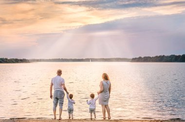 Sunset ve sailboa izlerken mutlu aile arkadan görünümü