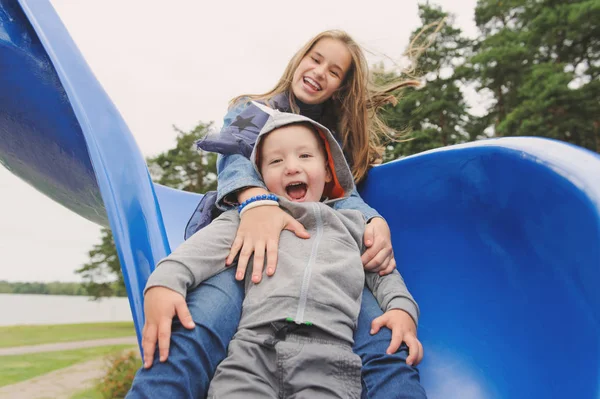 Lächeln Mädchen und Jungen, die Spaß auf der Kinderrutsche haben — Stockfoto