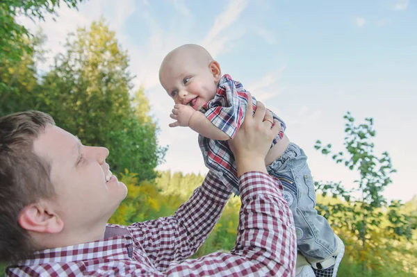 Glücklicher junger Vater, der seinen Sohn hochhebt — Stockfoto