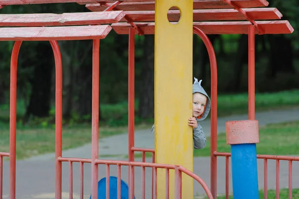 Menino a espreitar no parque infantil — Fotografia de Stock