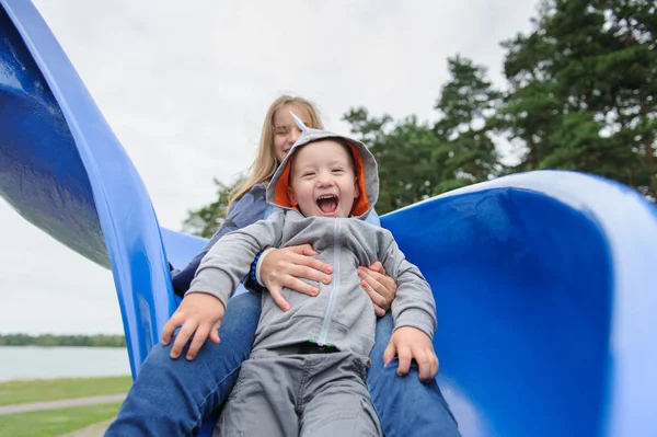 Sorrindo menina e menino se divertindo no slide das crianças — Fotografia de Stock