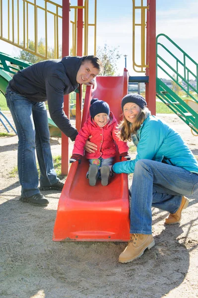 Eltern mit Tochter spielen an Kinderrutsche — Stockfoto