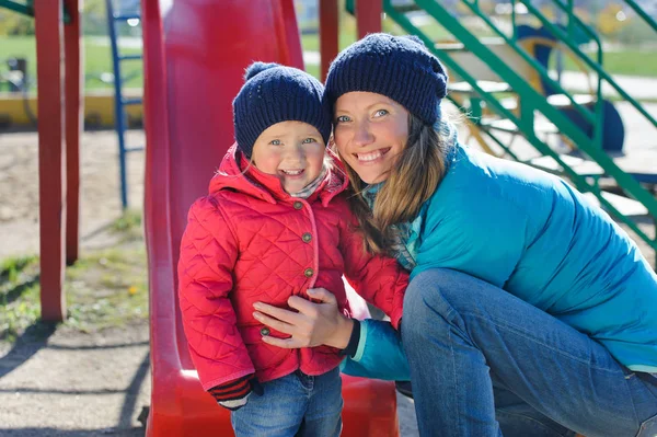 En liten flicka och hennes mamma som spelar i en lekplats — Stockfoto