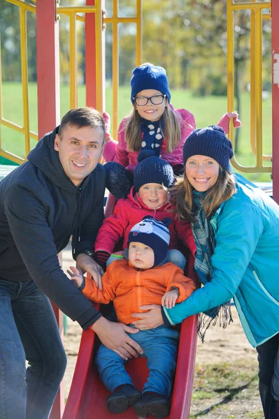 Ευτυχής χαμογελαστοί νεαρή οικογένεια των πέντε στο παιδική χαρά στο πάρκο — Φωτογραφία Αρχείου
