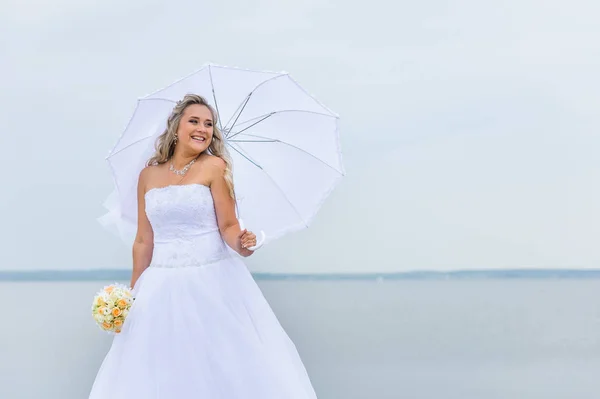 Beautiful bride in white dress with an umbrella