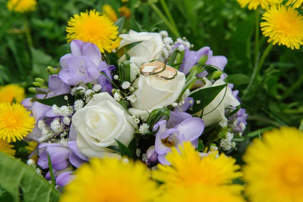 Wedding bouquet and wedding rings in dandelions — Stock Photo, Image