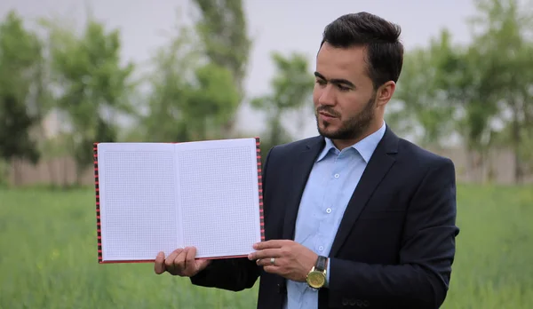 Bir sayfa boş kitap kentsel manzara fonunda tutan işadamı 