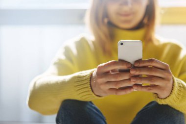 Rahat iç oturma ve modern smartphone aygıtı kullanarak genç hippi kız