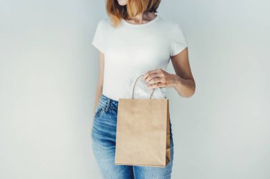 Boş beyaz t-shirt giyen ve kahverengi zanaat paket tutan genç kız