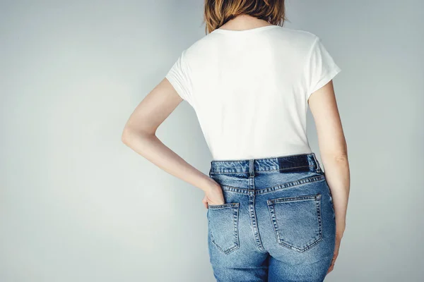 Kobieta nosi niebieskie jeansy z wysokiej talii i pusty biały t-shirt — Zdjęcie stockowe