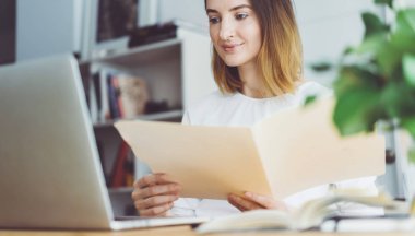 Onun ofisinde belgelerle çalışma ve modern dizüstü bilgisayar kullanan profesyonel iş kadını