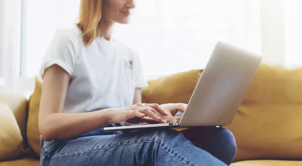 집에서 앉고 있는 동안 노트북에 메시지를 입력 하는 매력적인 여성 — 스톡 사진