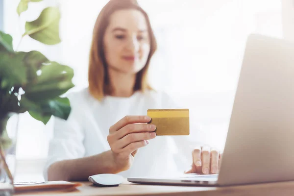Glückliche Frau nutzt Laptop und goldene Kreditkarte für Online-Einkäufe im Büro — Stockfoto