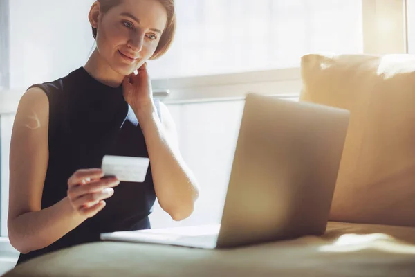 Lächelndes junges Mädchen mit goldener Kreditkarte in der Hand, die es für Online-Einkäufe von zu Hause aus benutzt — Stockfoto