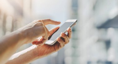 Erkek close-up ekran akıllı telefon arka planda, cep telefonunu şehir merkezinde iş kadın yazarak iletilerde şehirde işaret parmağı eller