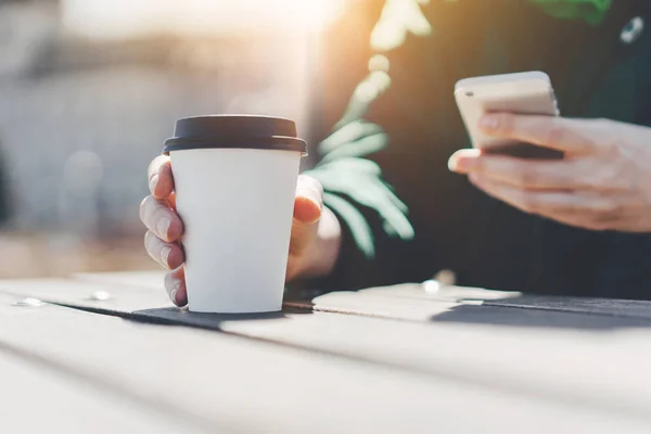 Wanita hipster menikmati kopi untuk pergi dan menggunakan ponselnya di luar, Hipster wanita mengetik pesan kepada teman-temannya dari ponsel pintarnya — Stok Foto