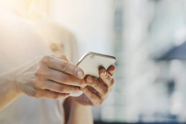 Young hipster girl typing sms message on touch screen of cellphone, Hipster girl wearing white t-shirt and using smart phone at sunny day — Stock Photo, Image