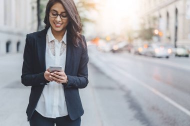 Öğle yemeği zamanı sırasında yürüyüş ve akıllı telefon açık kullanarak çekici genç kadın Yöneticisi