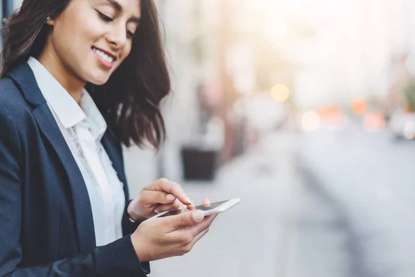 Image recadrée de femme d’affaires de succès heureux portant costume et en tapant le message via le téléphone intelligent tout en allant à son bureau — Photo