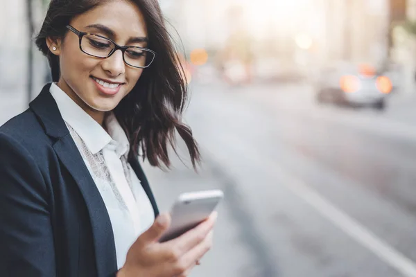 Portrait recadré d'une belle femme utilisant un smartphone tout en se promenant dans le centre-ville — Photo