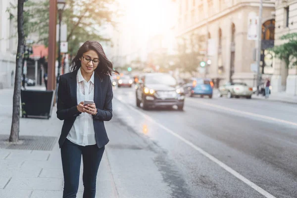 Succès banquier féminin travaillant en plein air via smartphone tout en marchant près de son bureau — Photo