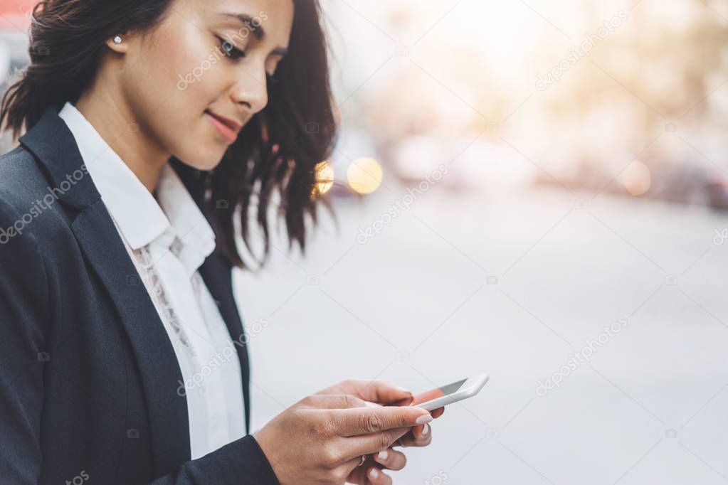 Smiling young business woman send an sms message to her business partner while going to office