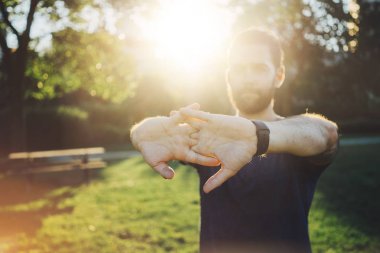 Gün batımında çalıştırmadan önce germe egzersiz yapan çekici sakallı erkek
