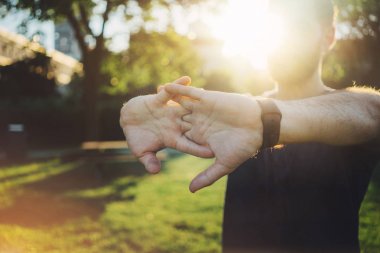 Genç adam parkta esneme egzersizi yapıyor.
