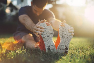 Onun yaz egzersiz yapmadan önce bacaklarını germe runner genç adam.