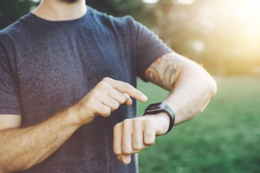 Genç adam akıllı seyretmek onu fitness ilerleme kontrol atış kırpılmış