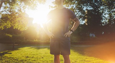 Genç çekici adam parkta günbatımında çalıştırdıktan sonra dinlenme