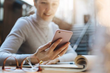 Modern ofiste otururken modern akıllı telefon kullanan kadın