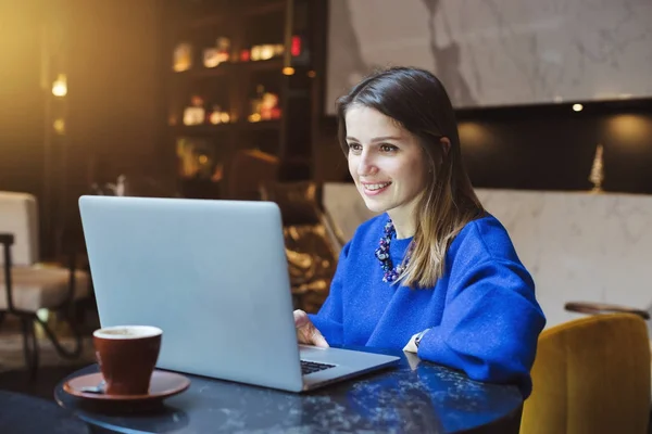 Happy woman using laptop while sitting at cafe