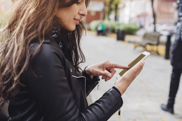 Genç güzel kadın işaret parmağı bir parkta bir bankta otururken ekran smartphone cep telefonu ile