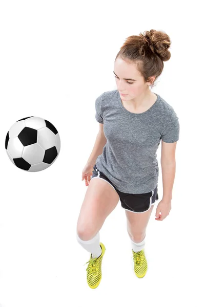 Chica adolescente con equipo de fútbol rebotando bola de su rodilla. Alto ángulo tiro aislado . —  Fotos de Stock