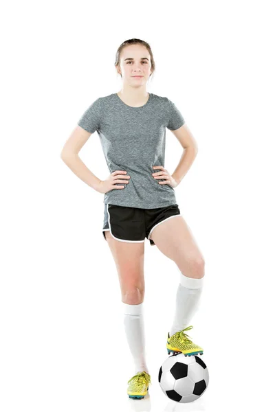 Dospívající dívka, která nosí fotbalové vybavení stojící nohou na fotbalový míč. — Stock fotografie