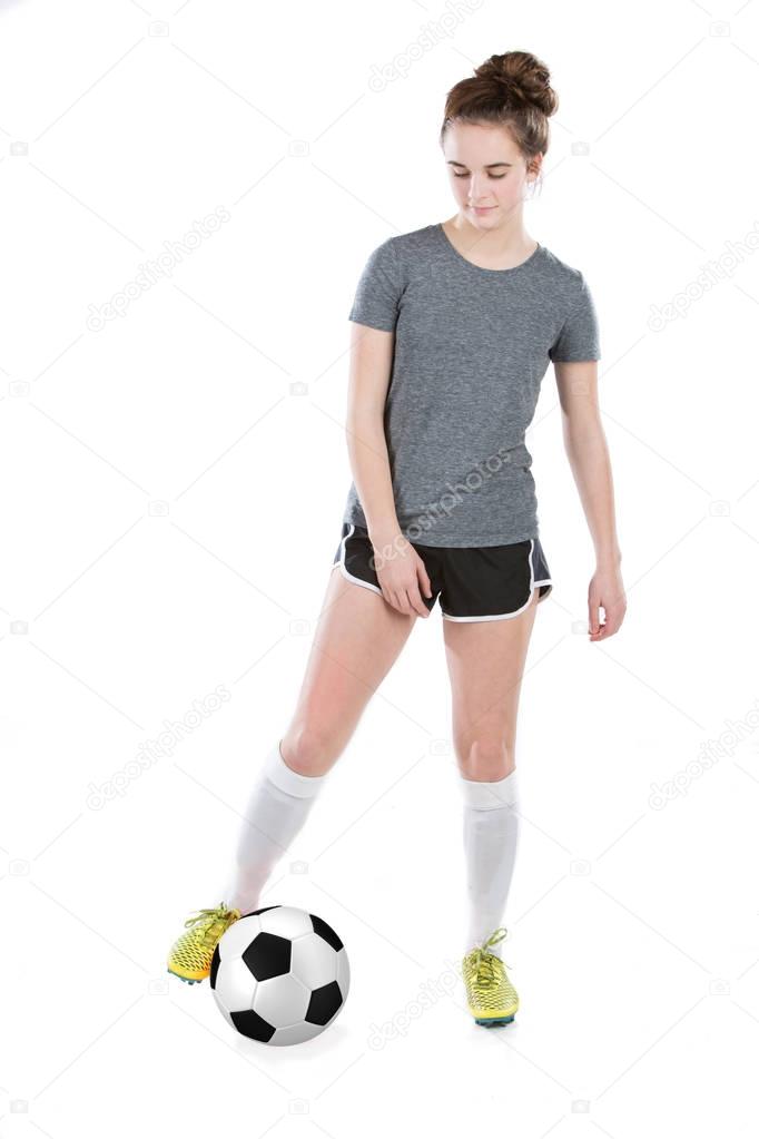 Teen girl moving soccer ball with her feet, wearing cleats and shinguards. 