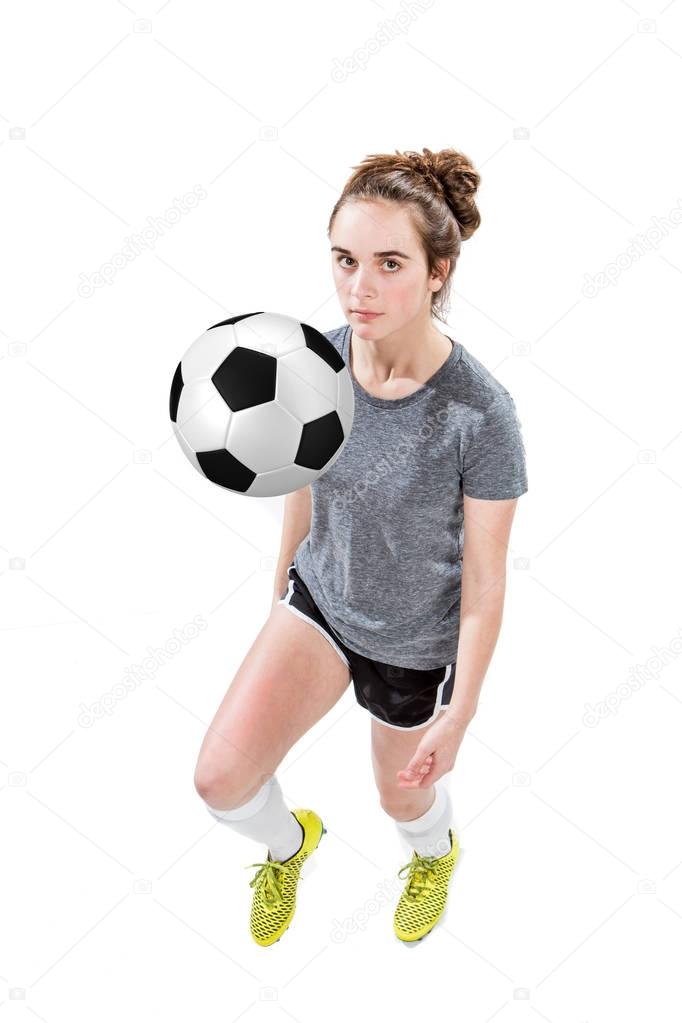 Athletic teen girl bouncing soccer ball off of her knee.