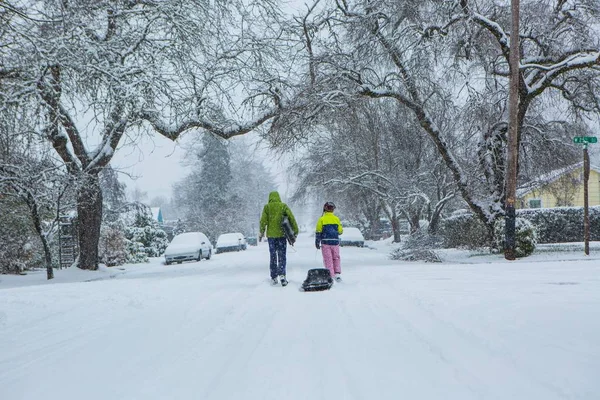 孩子们走在空荡荡的街道 拽着雪橇在刚倒下的冬天雪的中心 — 图库照片