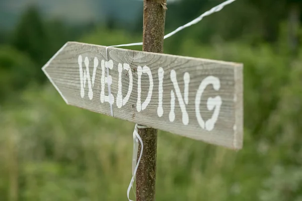 Old rustic sign pointing to a wedding.