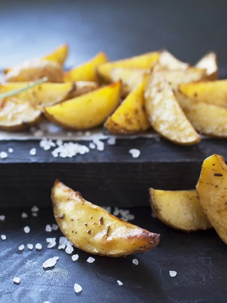 Oven baked spicy potato slices on wooden desk.