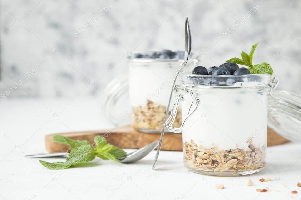 Granola with yogurt, mint and berries in jars.