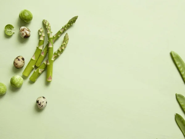 Brysselkål, sparris och vaktel ägg på optimistiska grön bakgrund. — Stockfoto