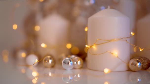 白色和金色的圣诞装饰点缀在明亮的灯火背景上 美丽的新年树 长着小球 家里还有白色的蜡烛和黄色的花环 — 图库视频影像