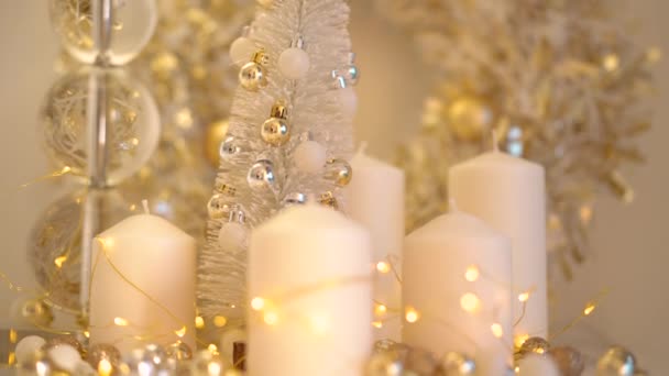 明るいボケのライトの背景に白と金の色でクリスマスの装飾 小さなボールで美しい新年の木 白いキャンドルと黄色のガーランドと家はまだ生活 — ストック動画