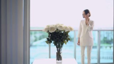 4k yaşam tarzı video güzel stil kadın telefon önünde konuşan beyaz güller buket. Çekici, kendine güvenen, beyaz iç çamaşırlı, esmer bir bayan. İç kısımda güzel güneş ışığı